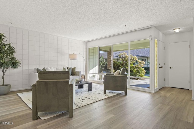 living room with a textured ceiling, tile walls, and hardwood / wood-style flooring