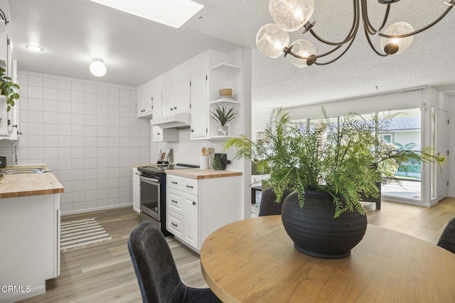 kitchen with white cabinets, electric stove, tile walls, butcher block countertops, and decorative light fixtures