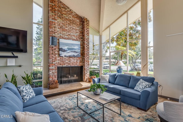 living room featuring a high ceiling, a brick fireplace, and plenty of natural light