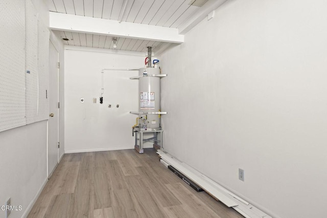 clothes washing area featuring light wood-type flooring, strapped water heater, and wooden ceiling