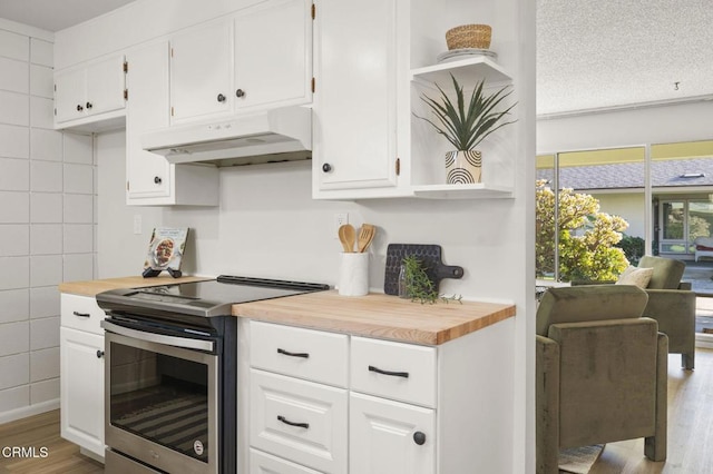 kitchen featuring stainless steel electric stove, white cabinets, light hardwood / wood-style floors, and tile walls