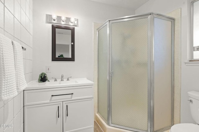 bathroom featuring vanity, toilet, and a shower with shower door