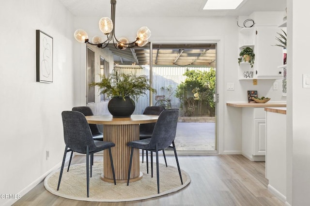 dining space with a notable chandelier, light wood-type flooring, and a skylight