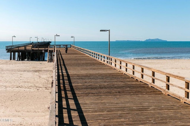 view of dock featuring a water view and a beach view