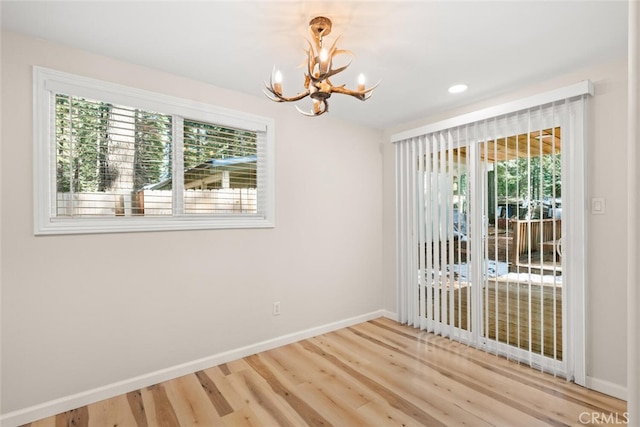 empty room featuring a chandelier, hardwood / wood-style flooring, and a healthy amount of sunlight