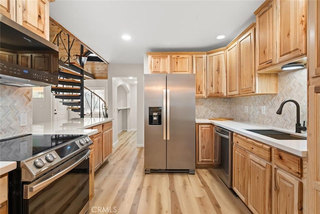 kitchen with sink, stainless steel appliances, range hood, backsplash, and light hardwood / wood-style floors