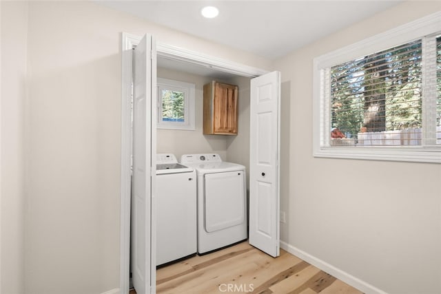 laundry room featuring cabinets, independent washer and dryer, and light hardwood / wood-style flooring