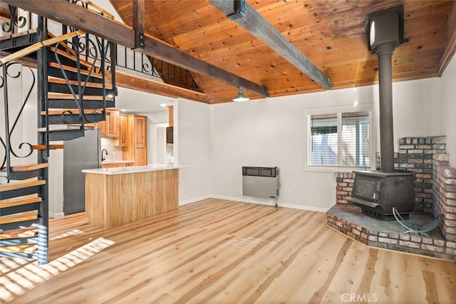 unfurnished living room with light wood-type flooring, heating unit, lofted ceiling with beams, wooden ceiling, and a wood stove