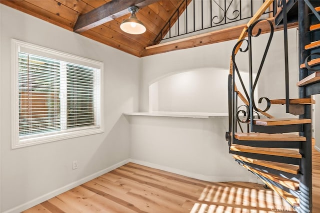 stairway featuring lofted ceiling with beams, hardwood / wood-style floors, and wood ceiling