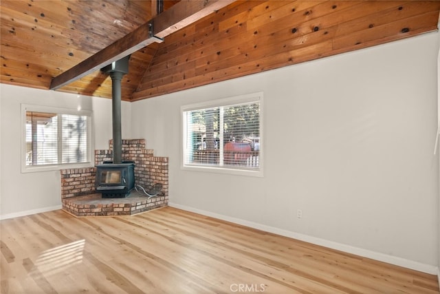 unfurnished living room featuring a wood stove, vaulted ceiling with beams, light hardwood / wood-style flooring, and wood ceiling