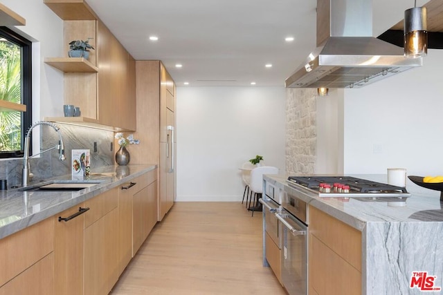 kitchen featuring sink, light stone counters, high end stove, exhaust hood, and light wood-type flooring