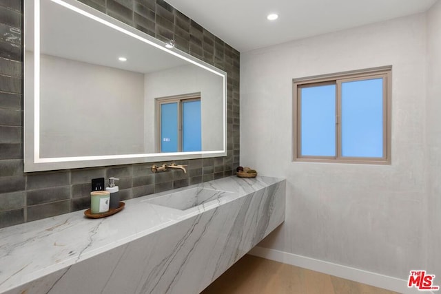 bathroom with backsplash, sink, and wood-type flooring