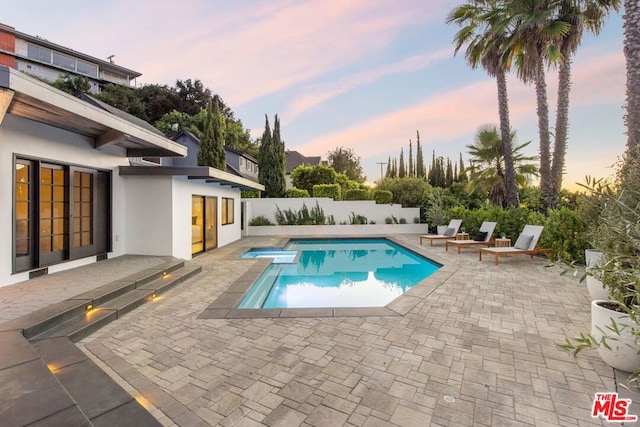 pool at dusk featuring a patio area