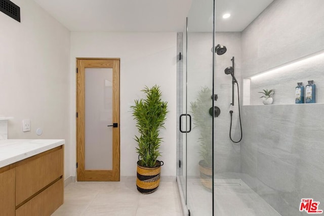 bathroom featuring tile patterned flooring, vanity, and a shower with door