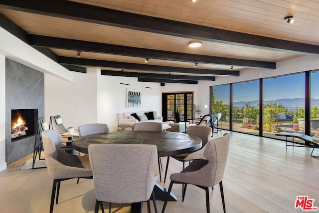 dining space featuring a mountain view, beam ceiling, light wood-type flooring, and wood ceiling