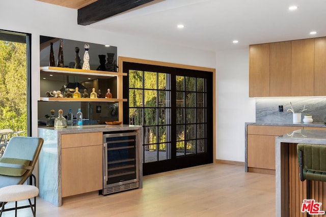 bar featuring light brown cabinets, light hardwood / wood-style floors, beam ceiling, and beverage cooler