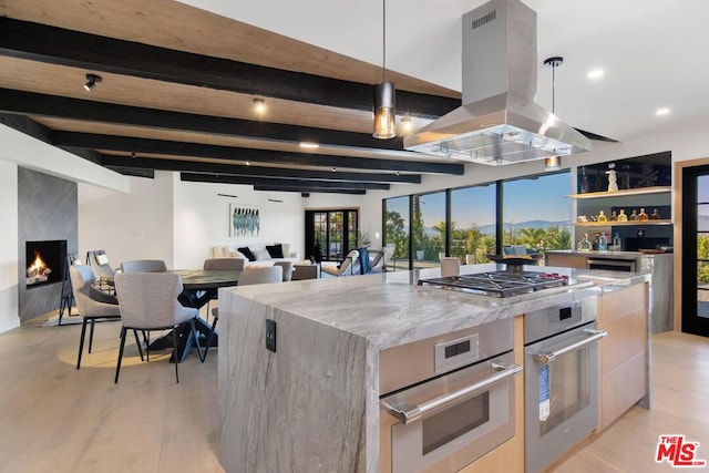 kitchen with island exhaust hood, a center island, light hardwood / wood-style floors, and appliances with stainless steel finishes