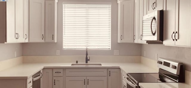 kitchen featuring stove, white cabinets, and sink