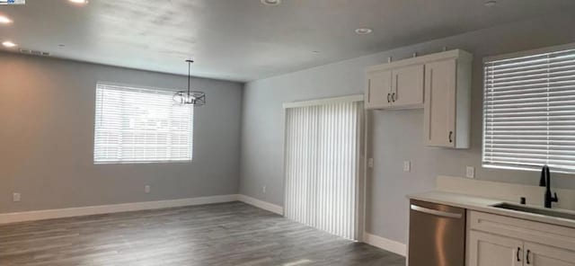 kitchen with white cabinets, dark wood-type flooring, sink, dishwasher, and hanging light fixtures