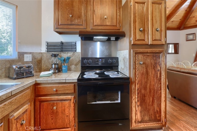 kitchen with wooden ceiling, black range with electric cooktop, lofted ceiling with beams, light hardwood / wood-style floors, and decorative backsplash