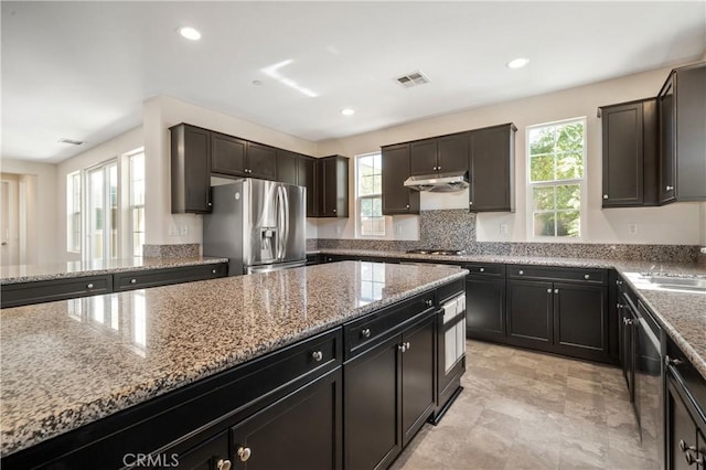 kitchen with dark brown cabinets, light stone countertops, and appliances with stainless steel finishes