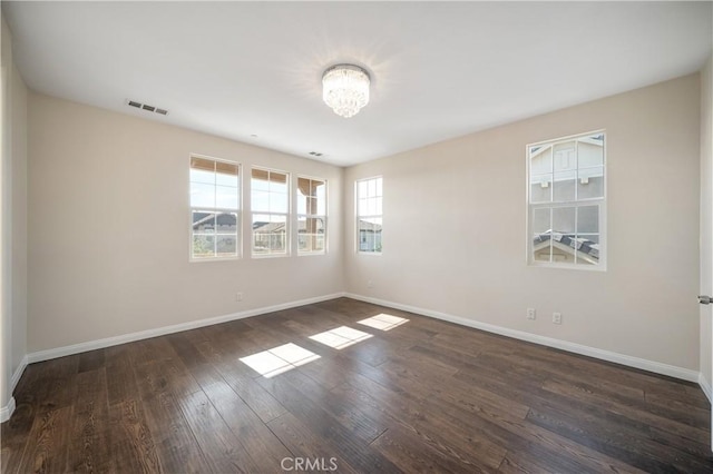 unfurnished room with a chandelier and dark hardwood / wood-style flooring