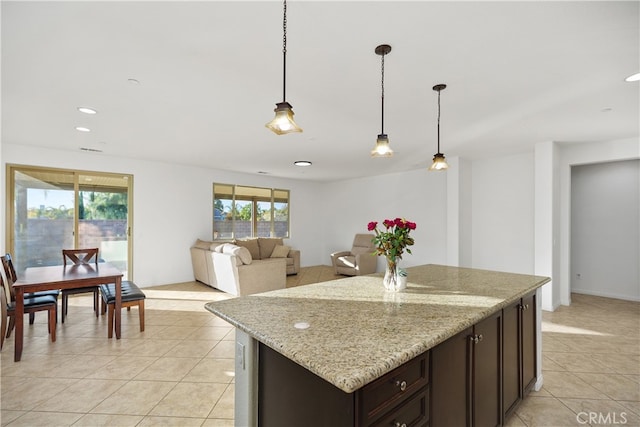 kitchen with a wealth of natural light, pendant lighting, and light stone counters