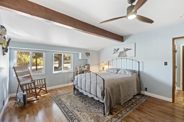 bedroom featuring wood-type flooring, lofted ceiling with beams, ceiling fan, and wood walls