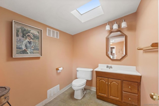 bathroom featuring tile patterned floors, vanity, toilet, and a skylight