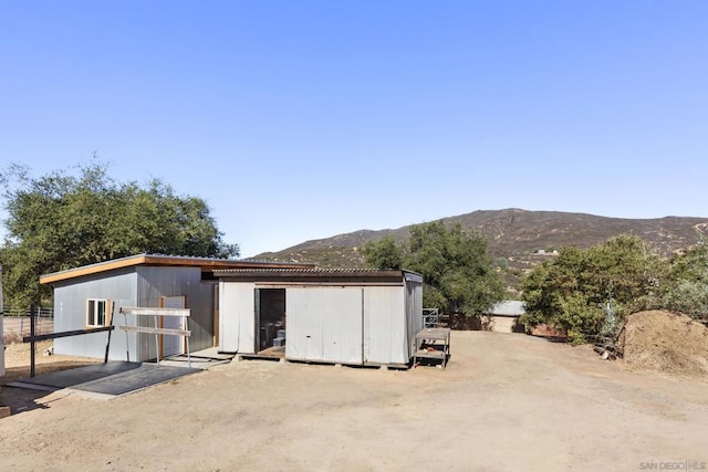 back of house featuring a mountain view and an outbuilding