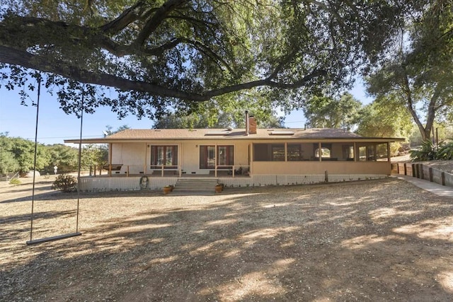 rear view of house with covered porch and solar panels