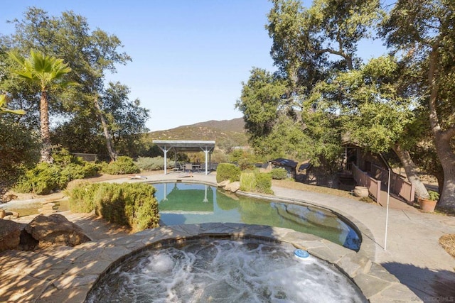 view of pool featuring a mountain view and an in ground hot tub