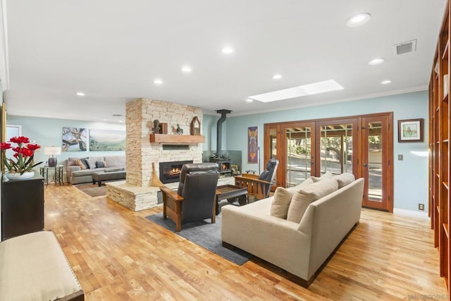 living room with a skylight, crown molding, french doors, and light hardwood / wood-style floors