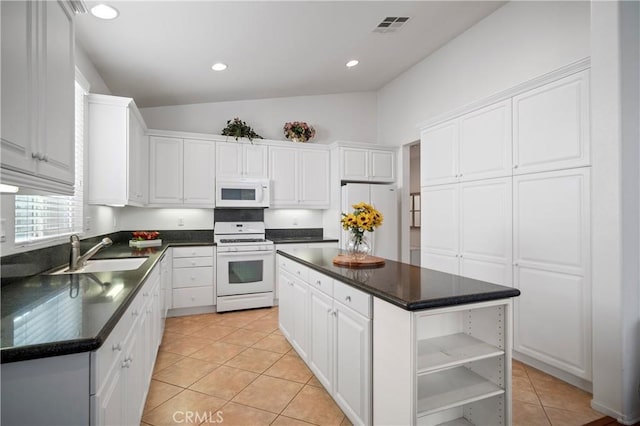 kitchen with a center island, light tile patterned floors, lofted ceiling, white appliances, and white cabinets