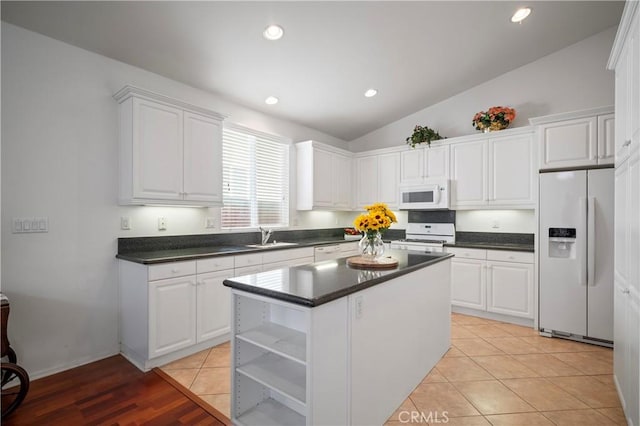 kitchen featuring white appliances, white cabinetry, and lofted ceiling