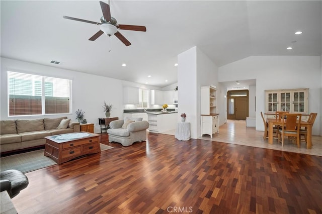 living room featuring lofted ceiling, ceiling fan, and dark wood-type flooring