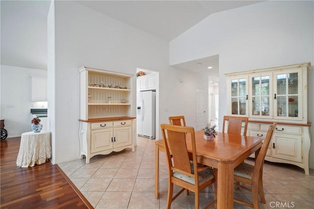 dining area featuring light hardwood / wood-style floors and high vaulted ceiling