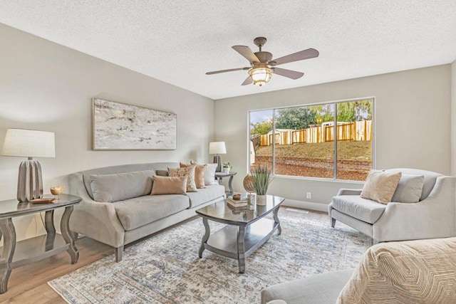 living room with ceiling fan, light hardwood / wood-style floors, and a textured ceiling