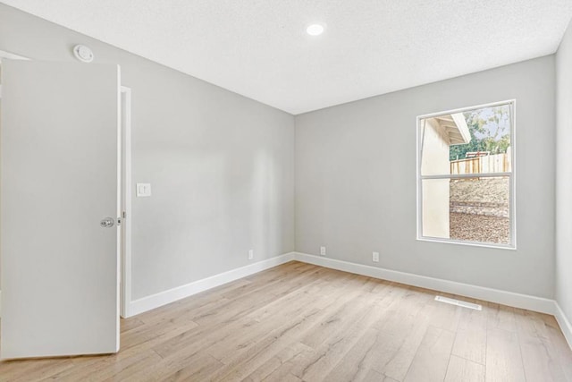 unfurnished room featuring light hardwood / wood-style floors and a textured ceiling