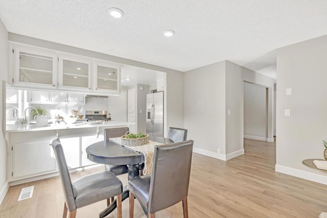 dining area featuring light hardwood / wood-style floors and a textured ceiling