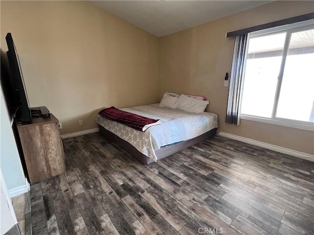 bedroom with multiple windows and dark hardwood / wood-style flooring