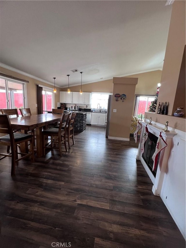 dining room featuring sink, dark hardwood / wood-style flooring, ornamental molding, and vaulted ceiling