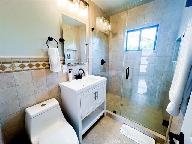 bathroom featuring vanity, a shower with door, tile patterned floors, toilet, and tile walls