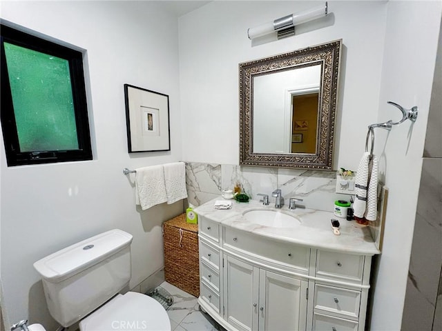 bathroom featuring vanity, toilet, and backsplash