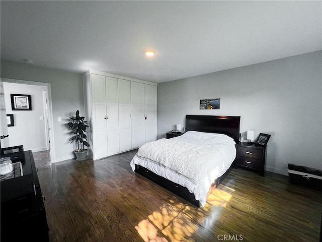 bedroom with dark wood-type flooring and a closet