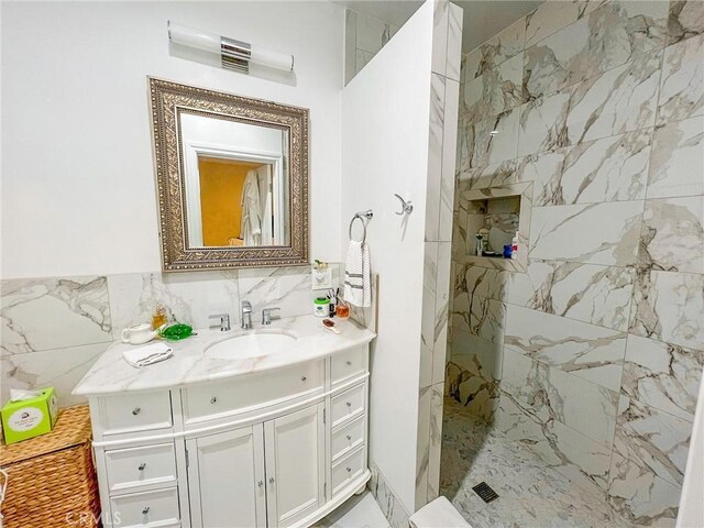 bathroom featuring a tile shower, vanity, and tile walls