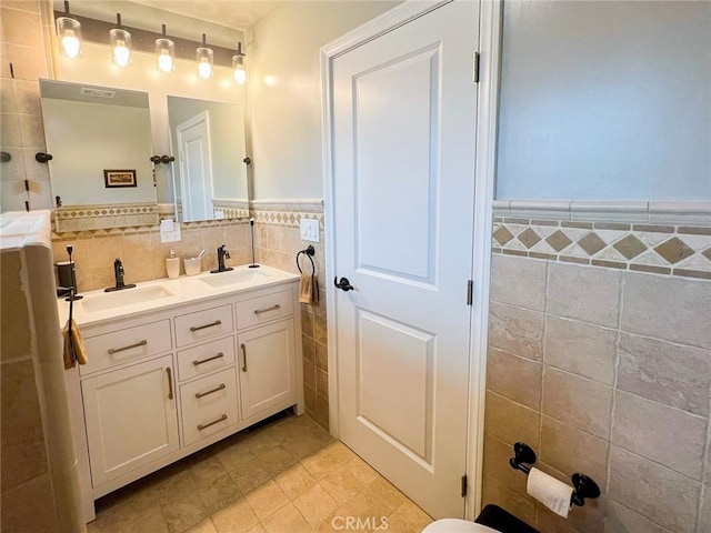 bathroom featuring tile patterned flooring, vanity, and tile walls