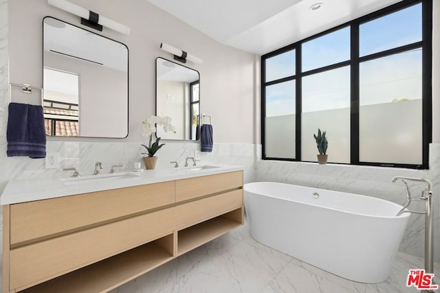 bathroom with a tub, plenty of natural light, vanity, and tile walls