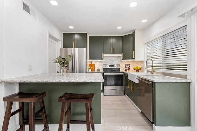 kitchen with a breakfast bar area, light stone counters, sink, and stainless steel appliances