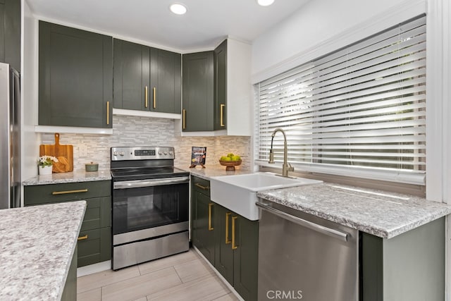 kitchen featuring light stone counters, sink, appliances with stainless steel finishes, and green cabinetry